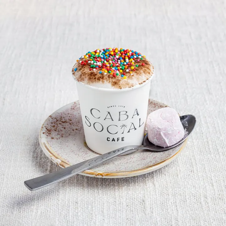 Babycino with chocolate dusting and a pink marshmallow, served in a Caba Social cup