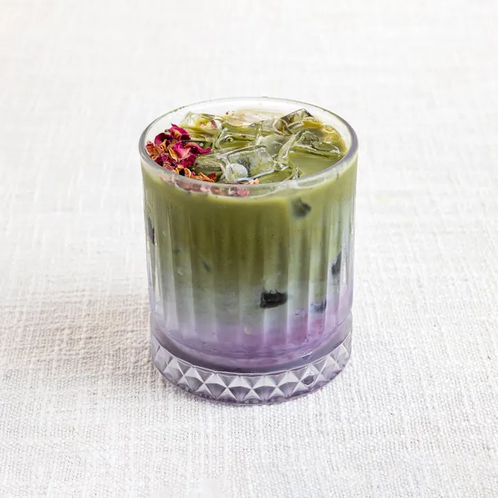 Iced blueberry matcha in a ribbed glass, matcha green over a violet berry layer