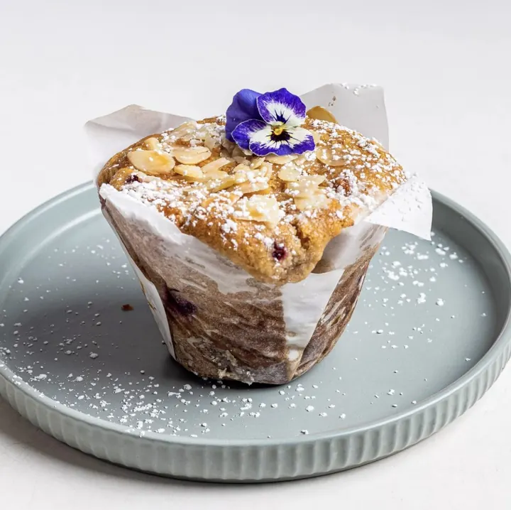 Glazed muffin dusted with icing sugar on a stone plate