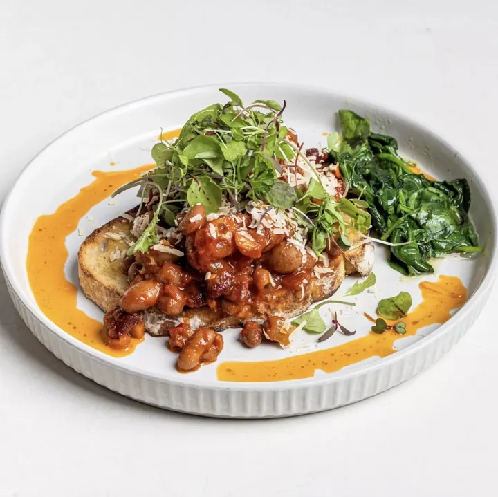 Spiced beans on sourdough toast with wilted greens and shaved cheese