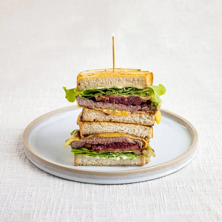 Steak sanga stacked high on toasted sourdough with a skewer through the middle
